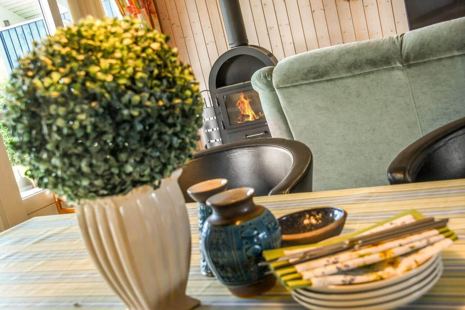 Tisch mit Geschirr, Pflanze und Kamin im Hintergrund.