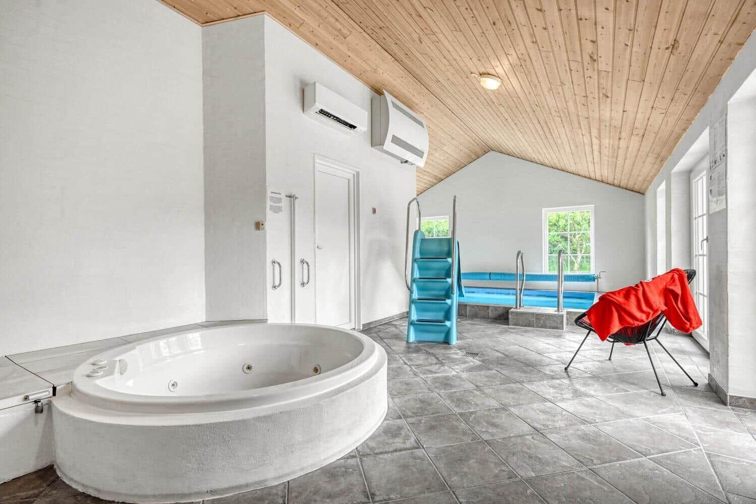 Innenpool mit Whirlpool, blauer Treppe und rotem Stuhl
