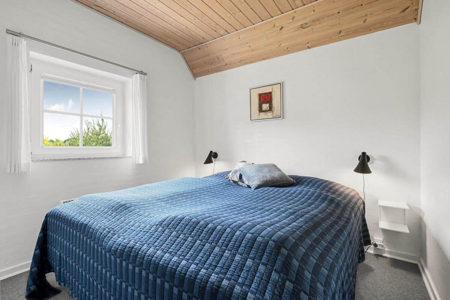Schlafzimmer mit Bett, Fenster und Holzdecke