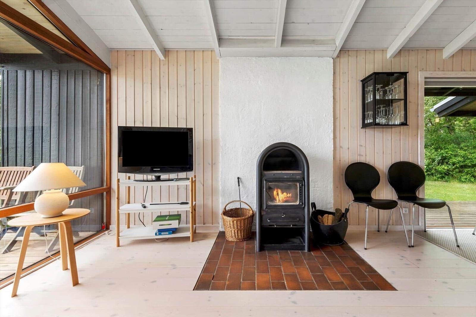Living room with fireplace, TV, and seating. Wooden walls and terrace door.