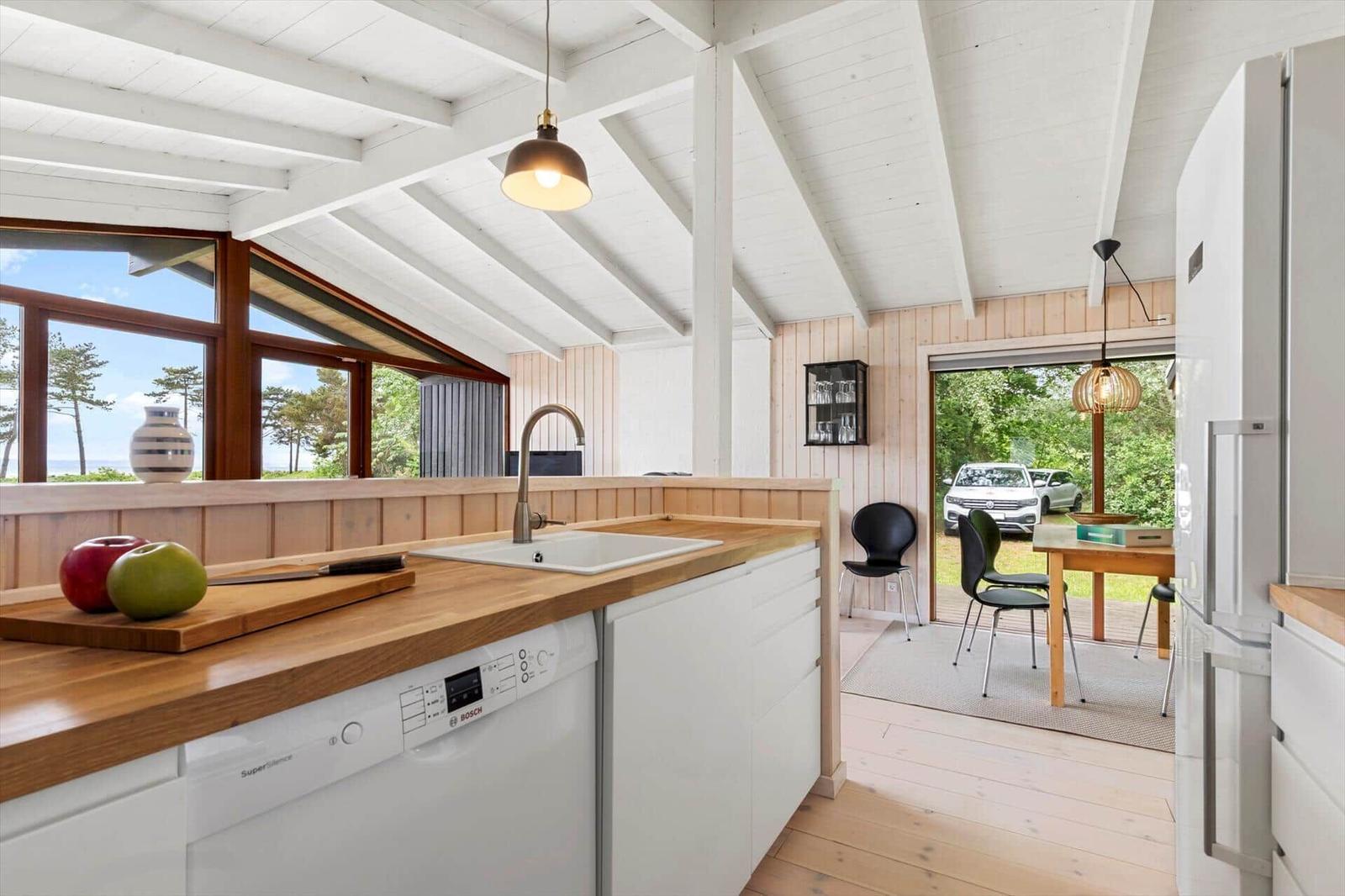 Kitchen with wooden countertop and view of garden. Dining area with table and chairs.