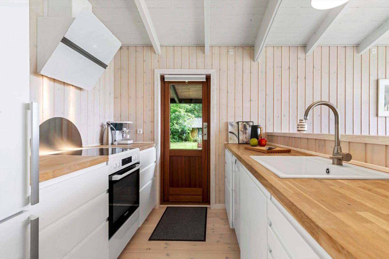 Kitchen with wooden surfaces, white cabinets, and view of garden
