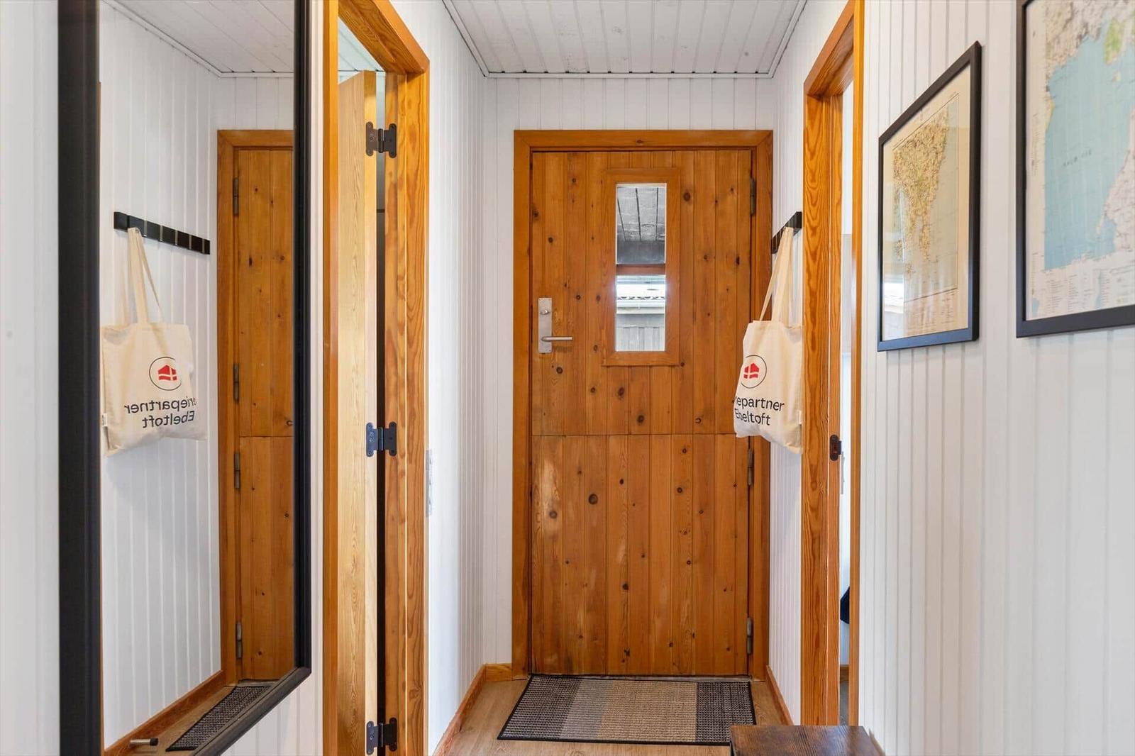 Hausgang mit Holztür und Wandkarten. Beide Türen haben Haken mit Taschen.