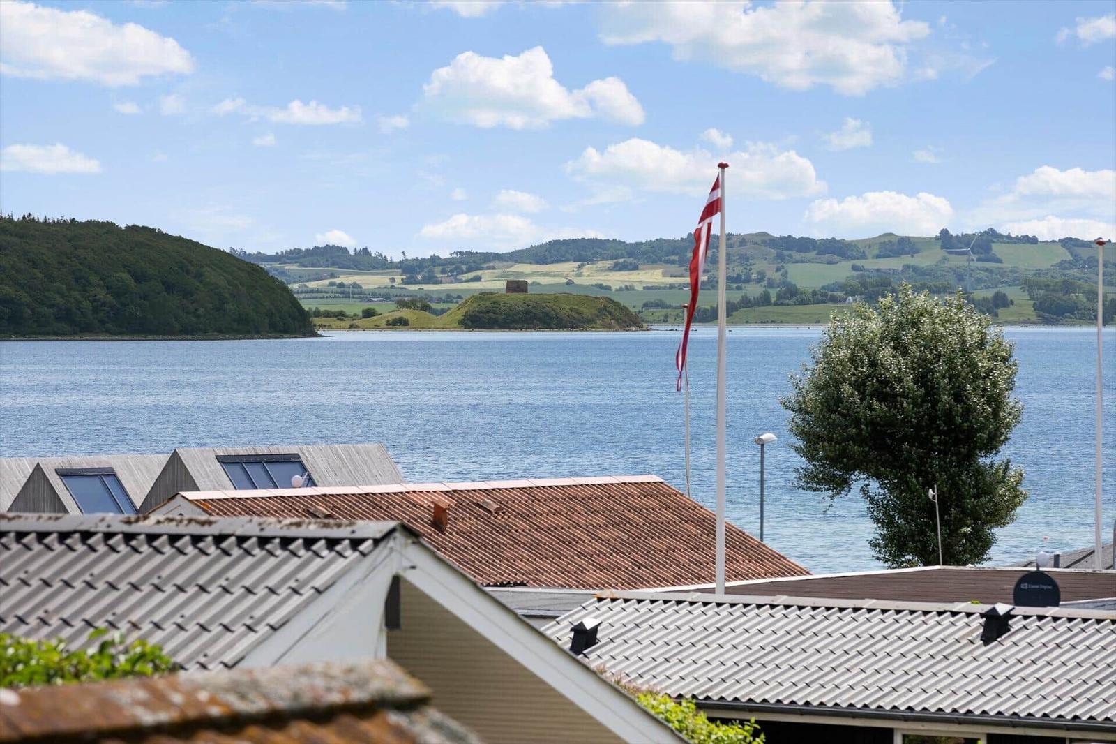 Blick auf See mit Flagge und Hügeln im Hintergrund.