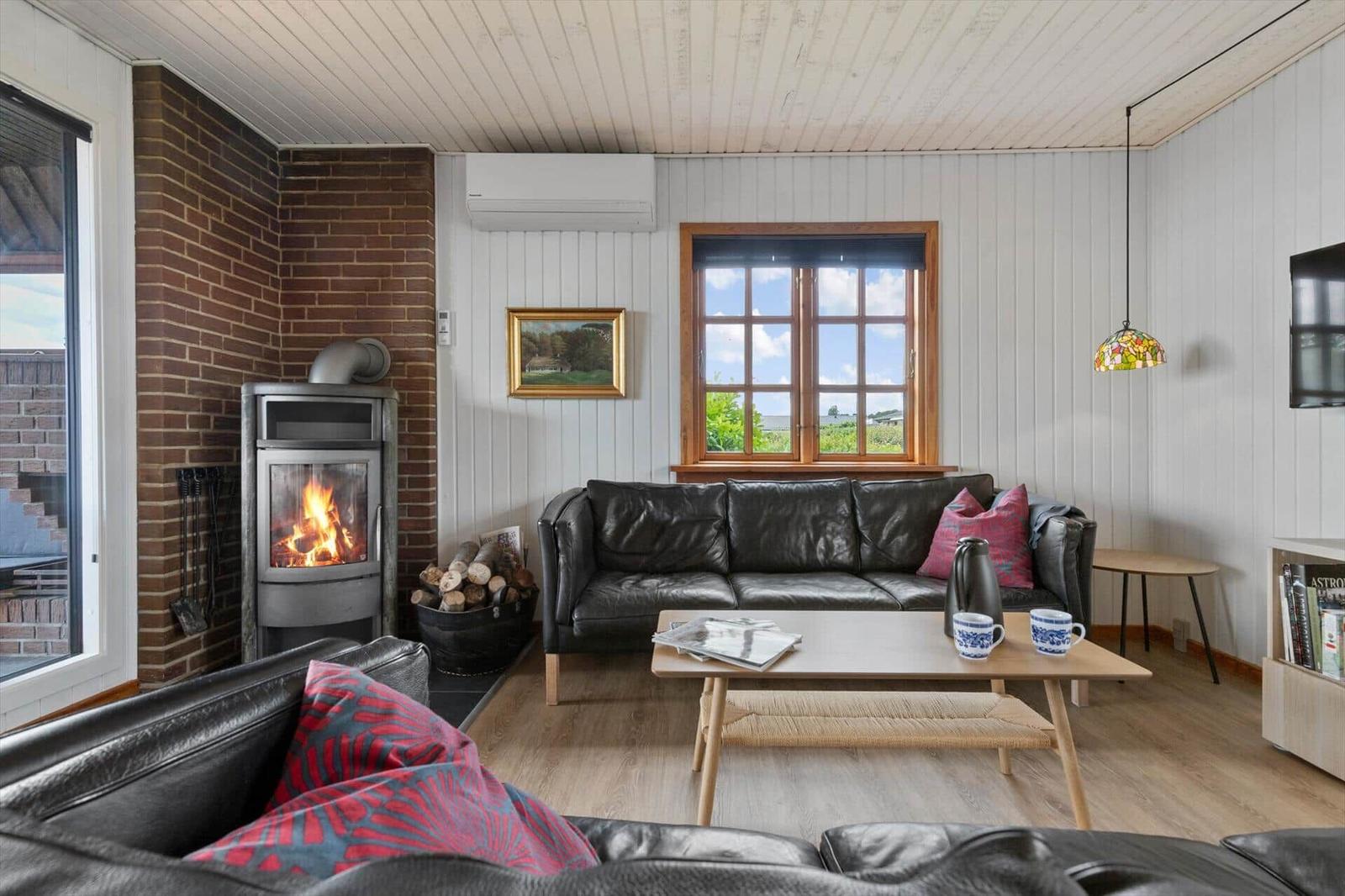 Wohnzimmer mit Kamin, Sofa und Fenster zum Garten
