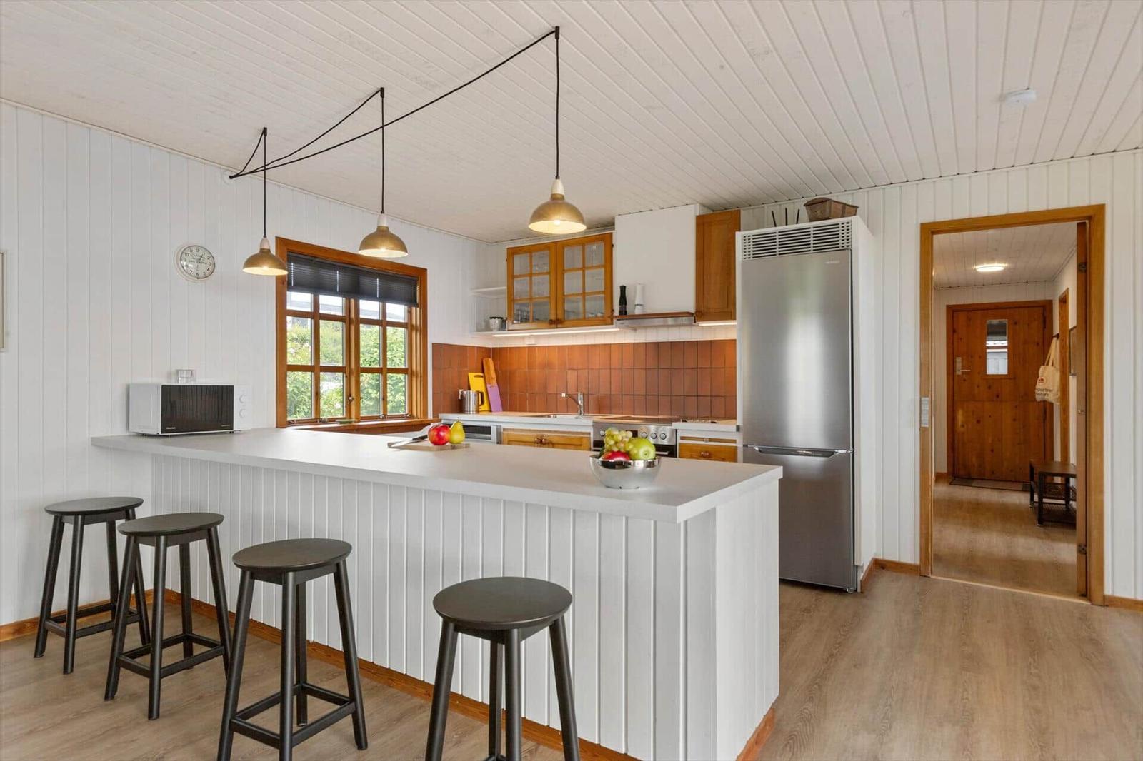 Küche mit Insel, Stühlen, Kühlschrank und Fenster.