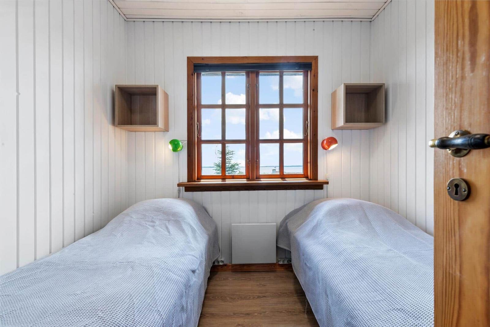 Zwei Betten unter einem Fenster mit Blick aufs Meer. Holzwände und -boden.