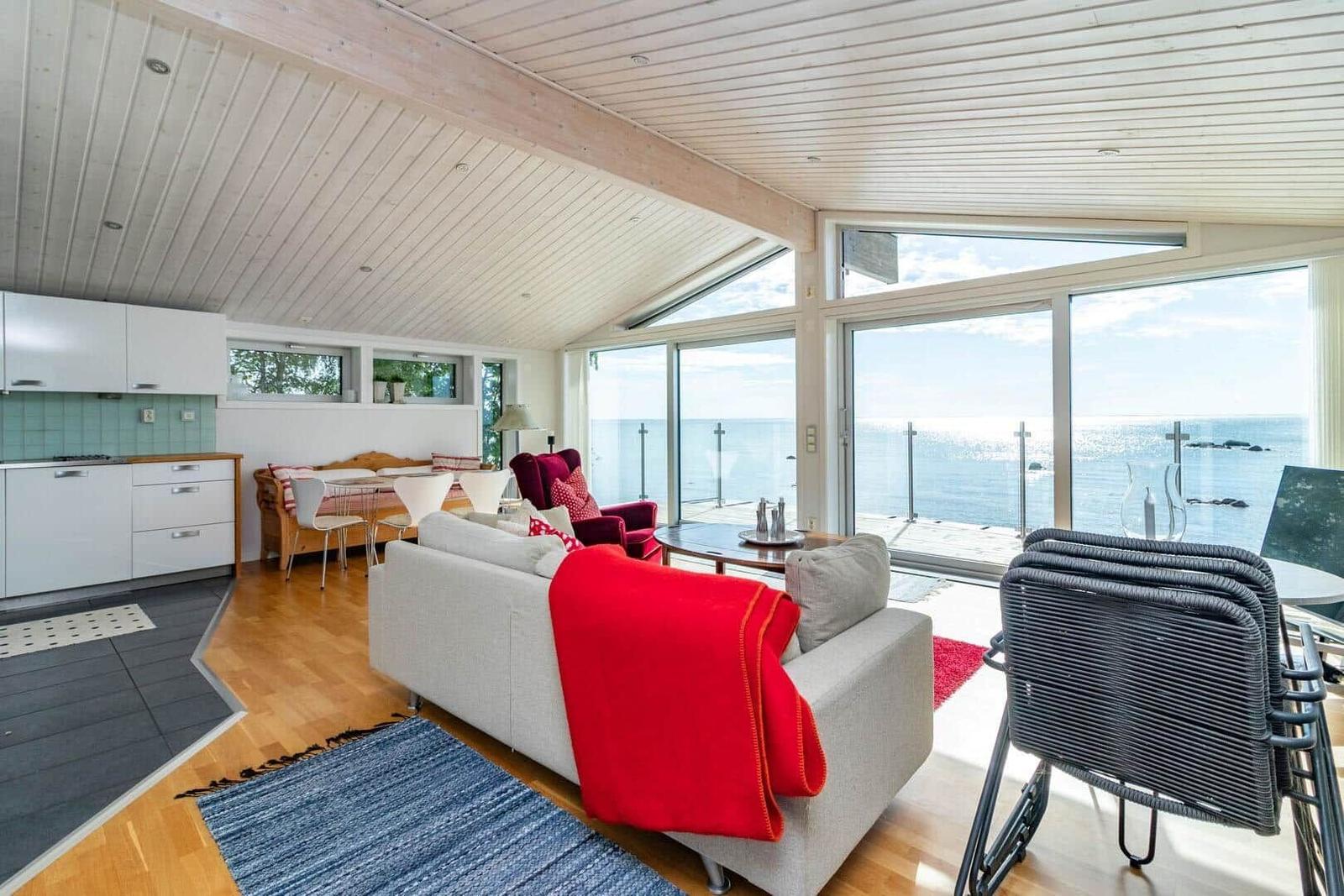 Wohnung mit Küchenbereich, Sofa und Meerblick durch große Fenster.