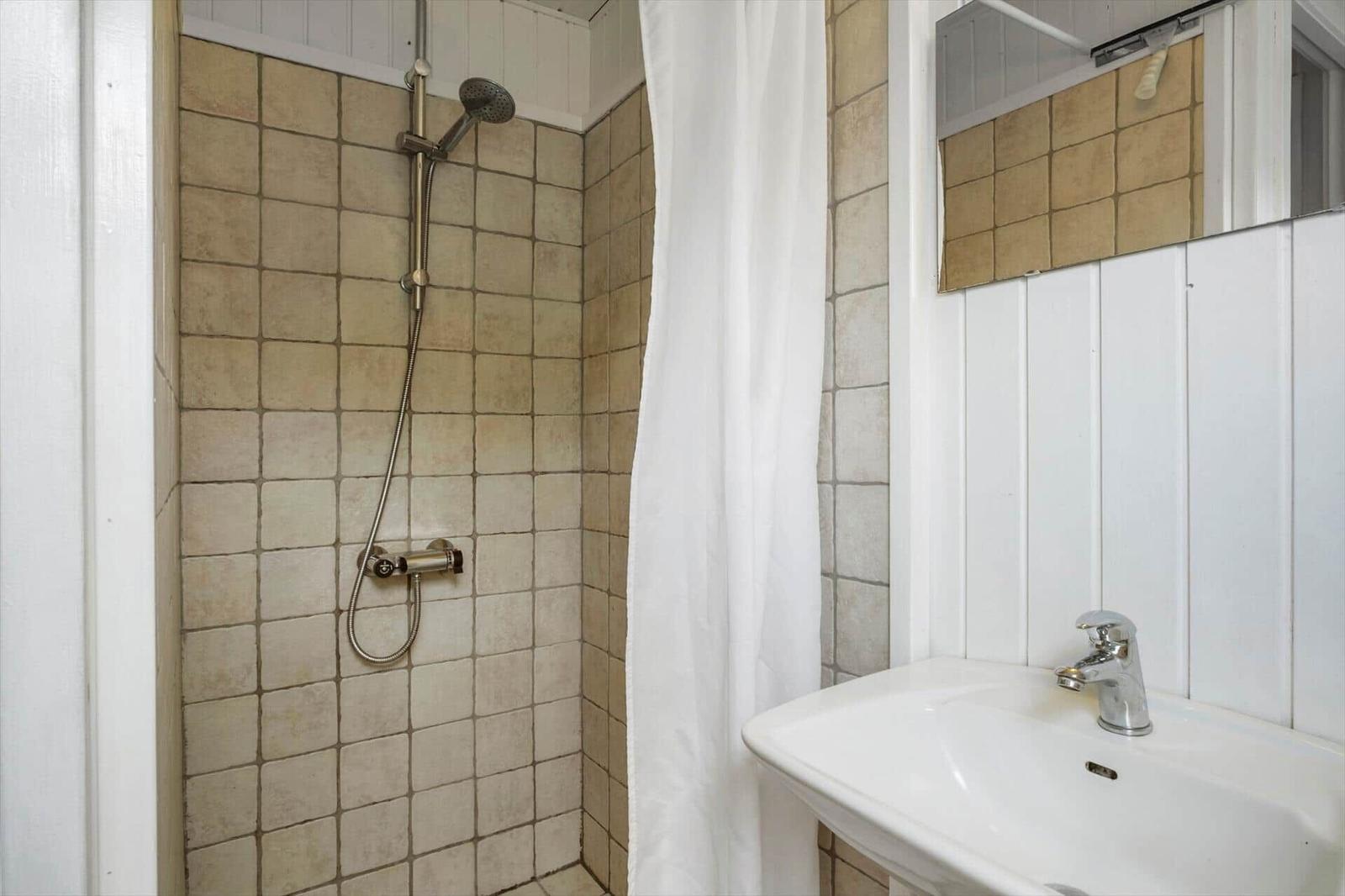 Dusche mit Duschbrause und Waschbecken mit Spiegel