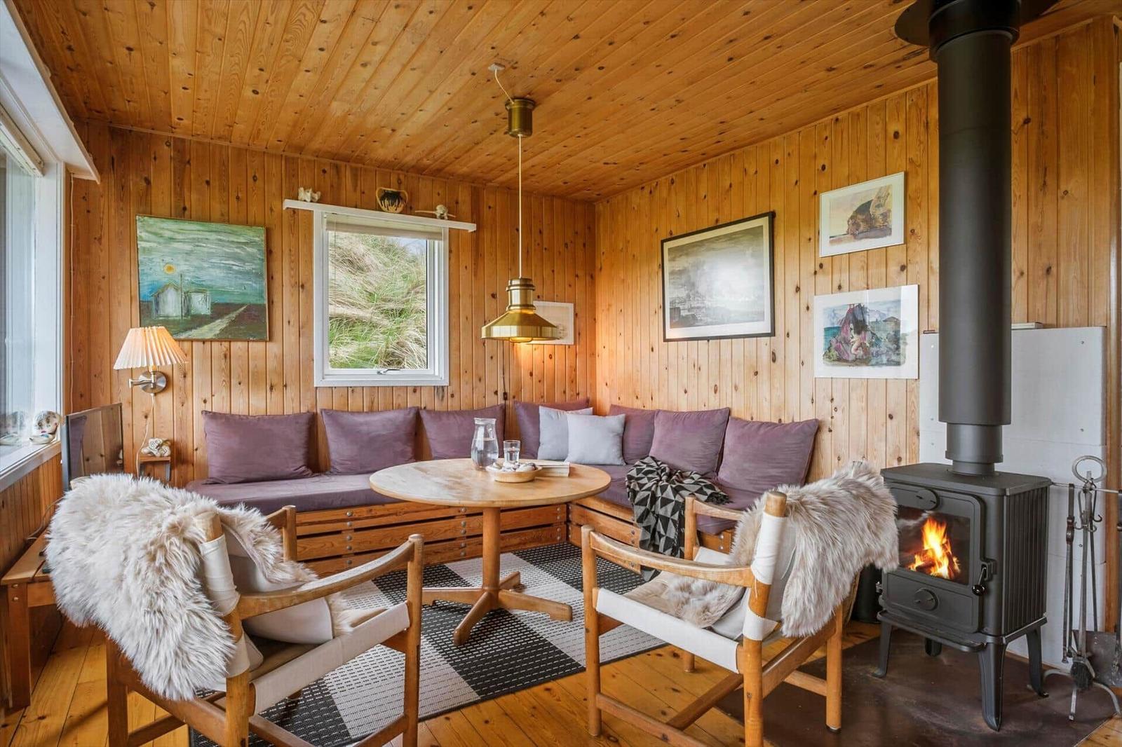 Ein Raum mit Holzwänden, einem Kaminofen und einem runden Tisch.