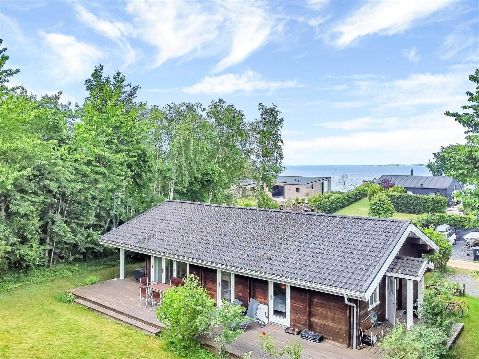 House with wooden deck and garden, view of lake and trees.