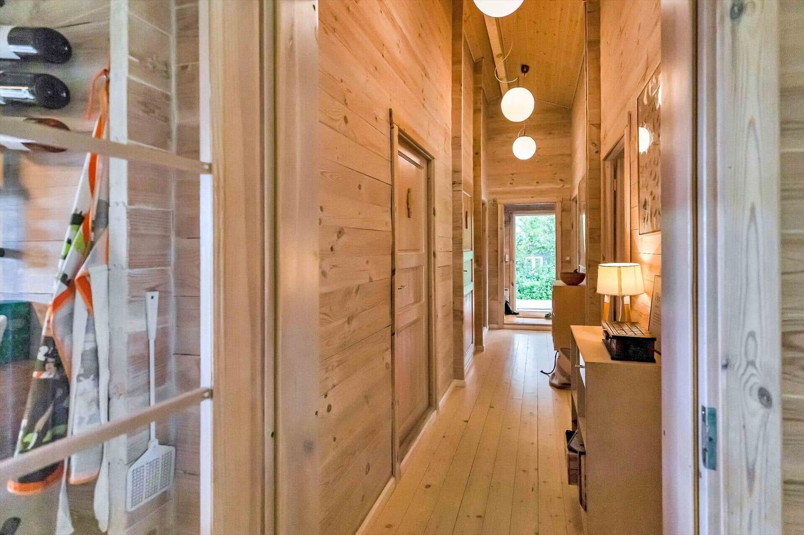 Wood-paneled hallway with lamp and door. Corridor leading to outdoor area.