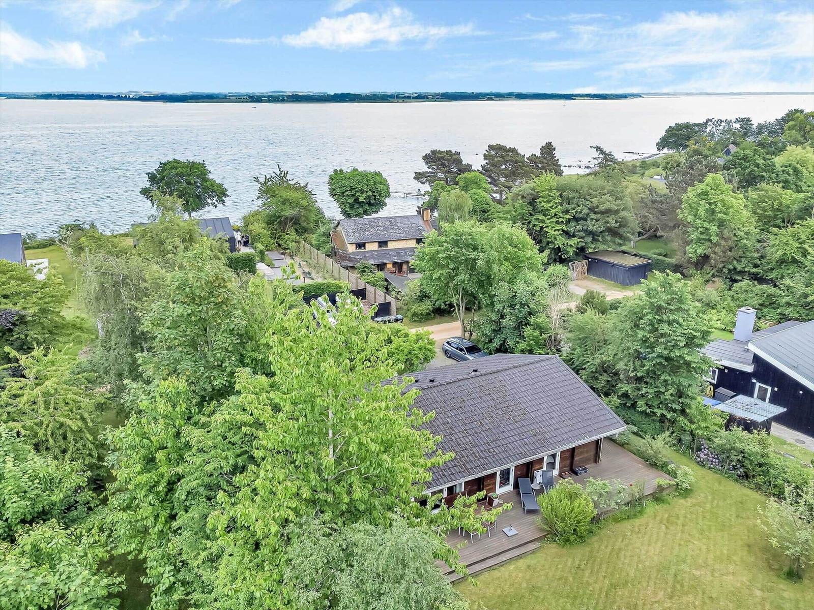 House with terrace and view of water and forest.