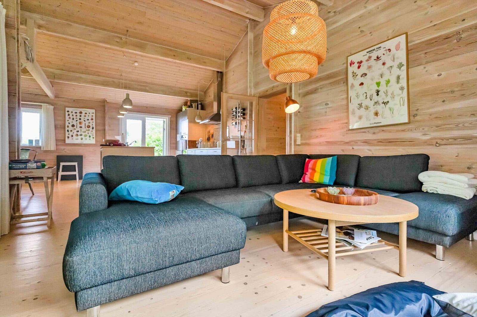 A living room with a gray sofa, a round table, and a wooden wall.