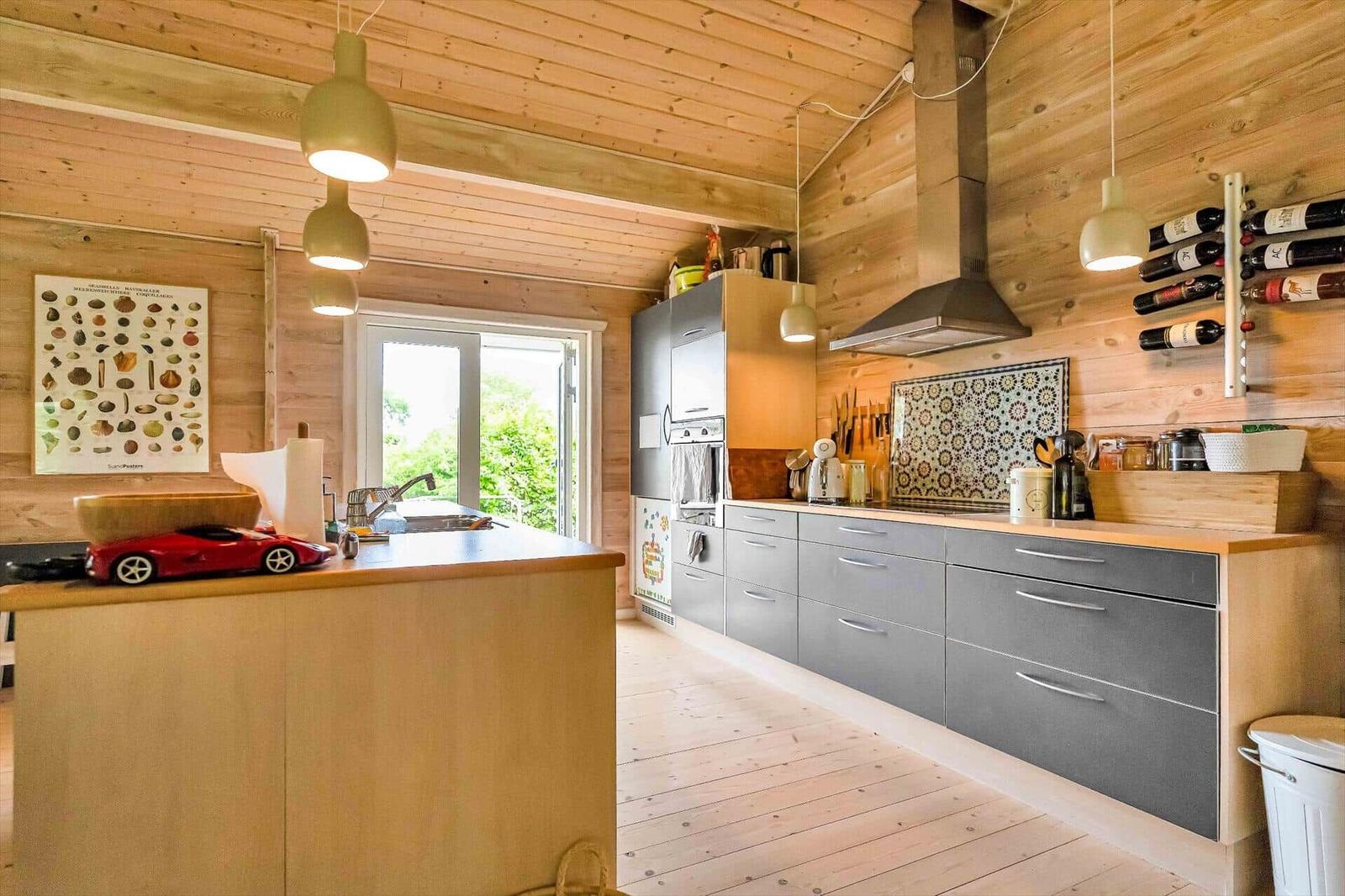 Kitchen with wooden walls, gray cabinets, and window to outside.