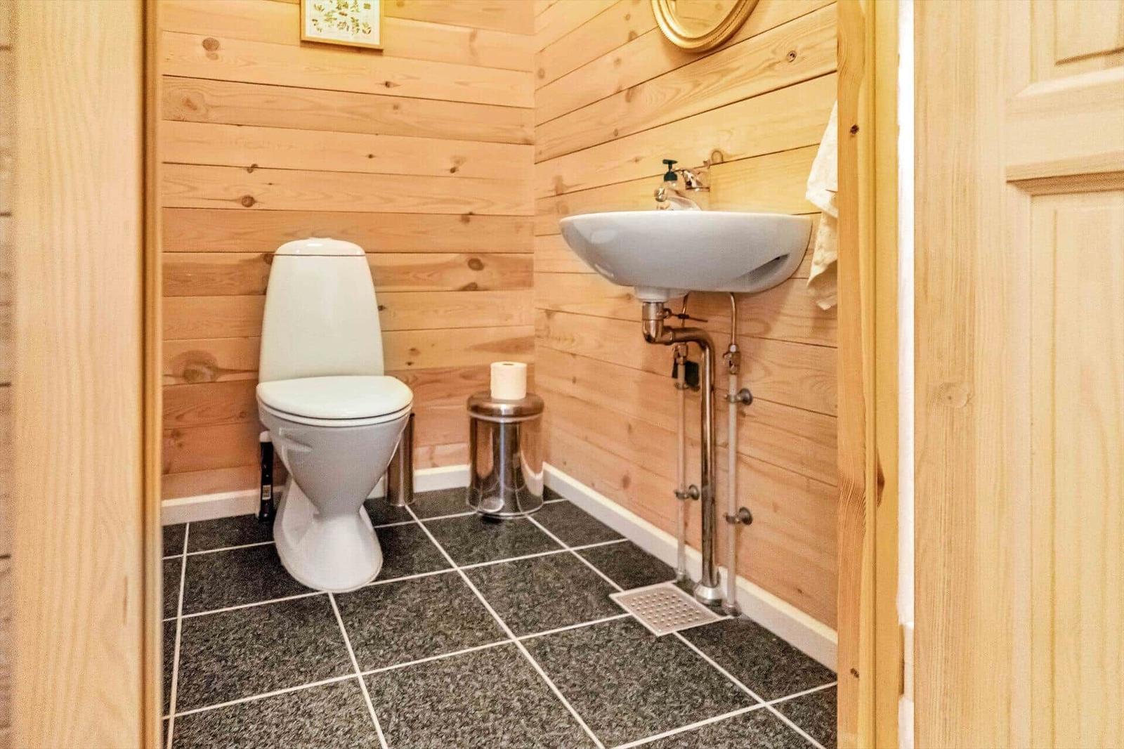 Bathroom with toilet, sink, and wood paneling.