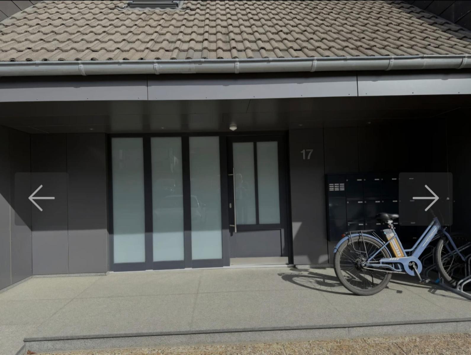 Eingang mit Glasfront und Fahrradständer. Hausnummer 17 an der Wand.