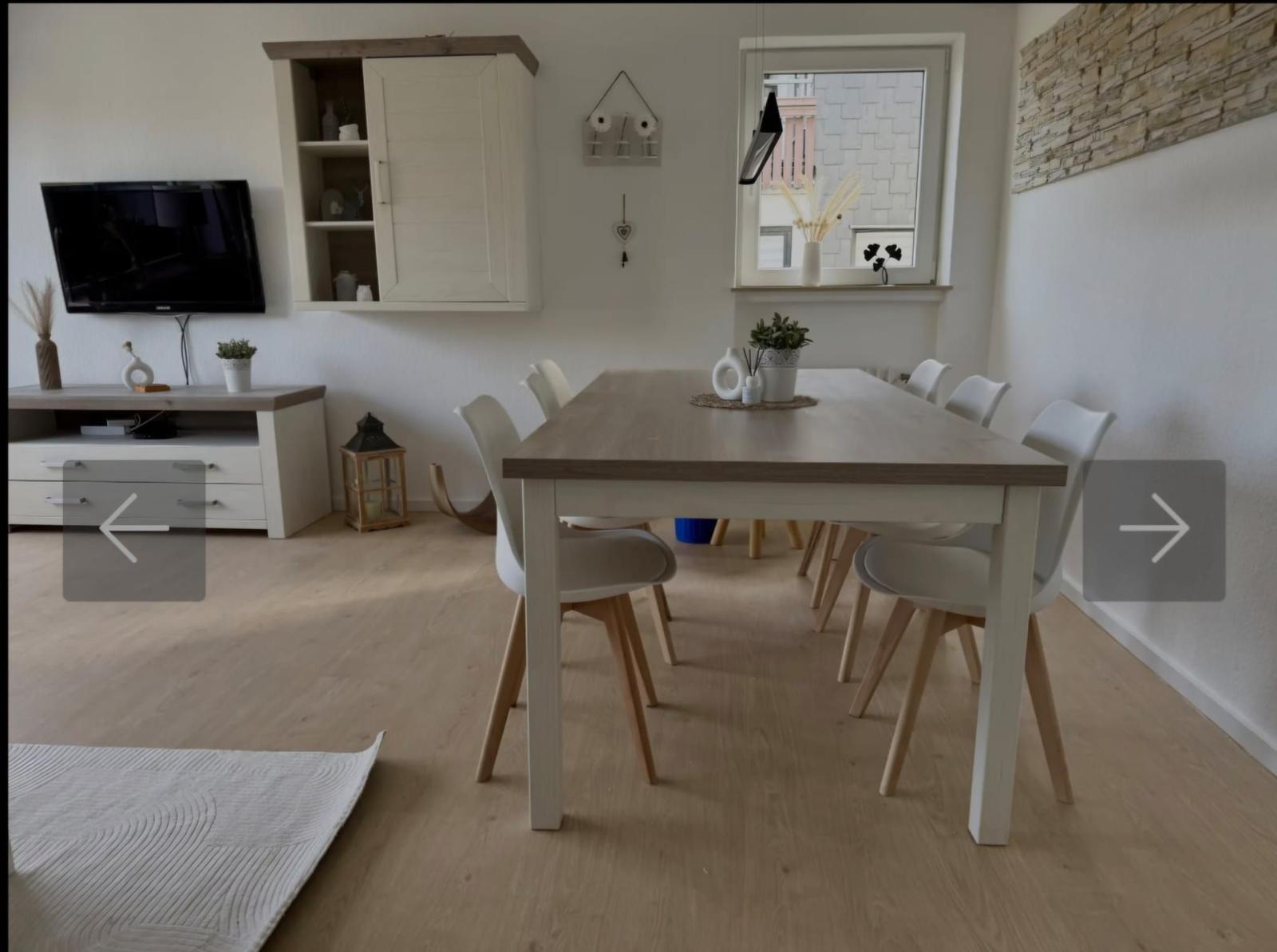 Essbereich mit Tisch und Stühlen, Fernseher und Schrank an der Wand.