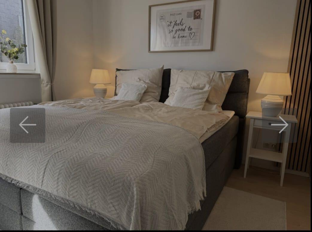 Schlafzimmer mit Doppelbett, zwei Nachttischen und Fenster mit Pflanze.