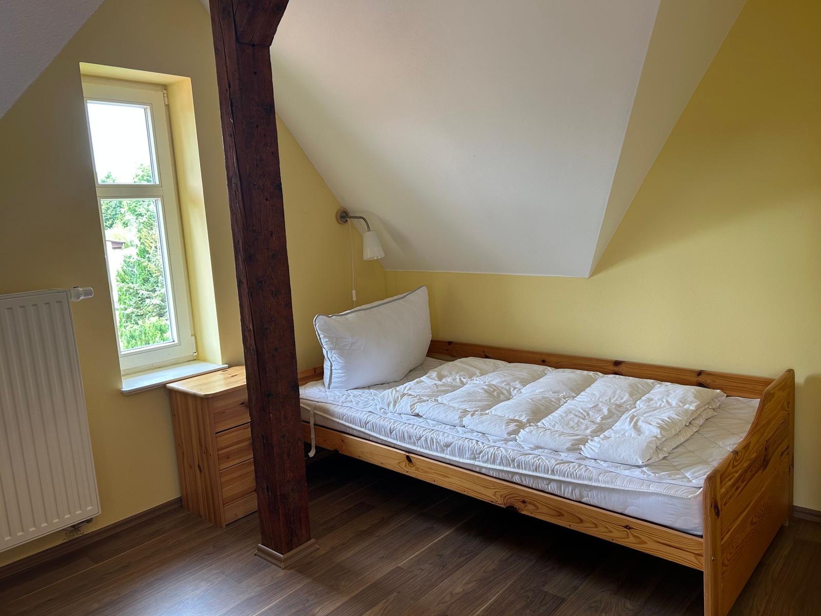 Schlafzimmer mit Holzbett, Fenster und Heizkörper