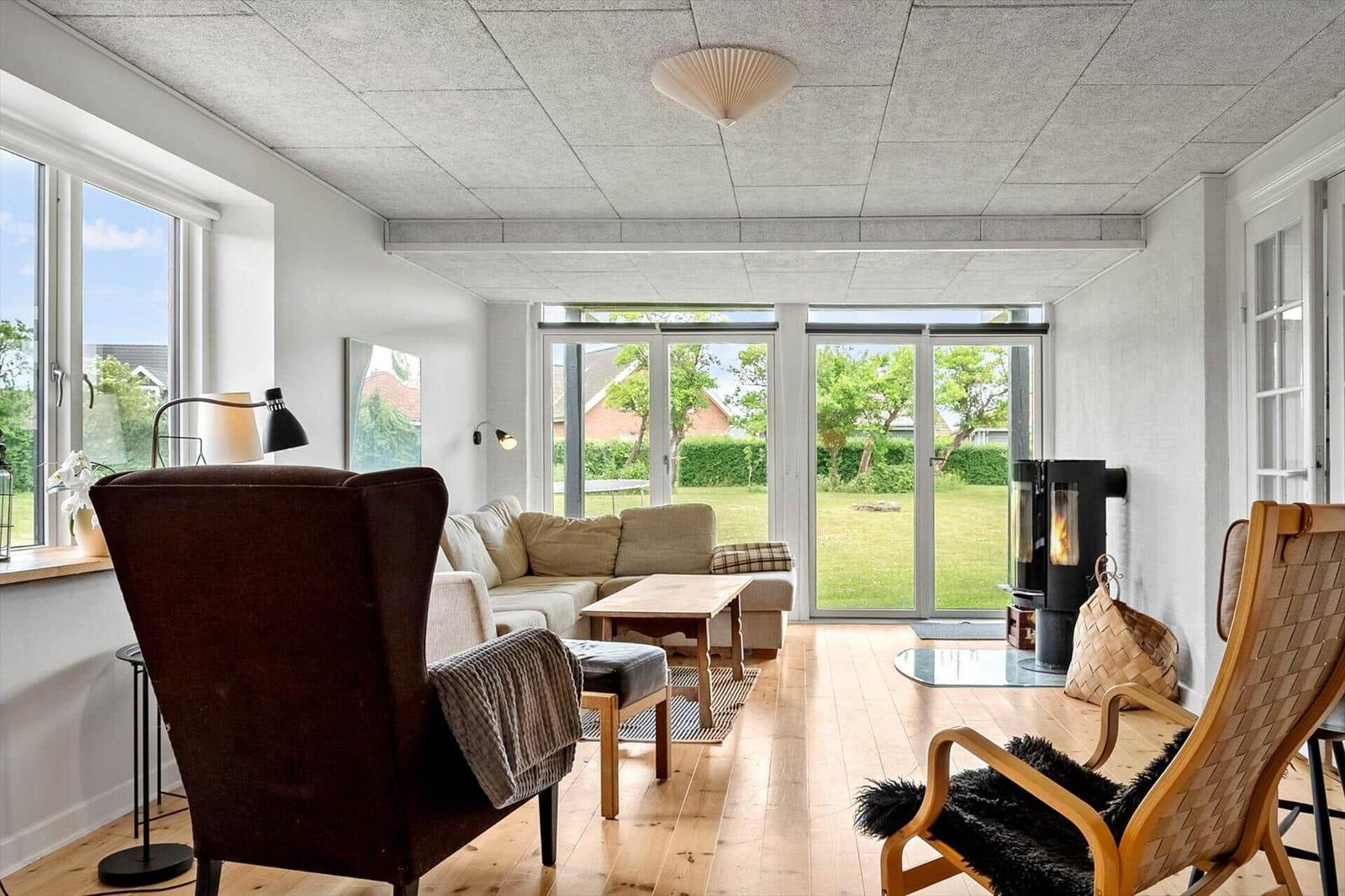 Wohnzimmer mit Sitzgelegenheiten, Holzboden und Blick auf den Garten.