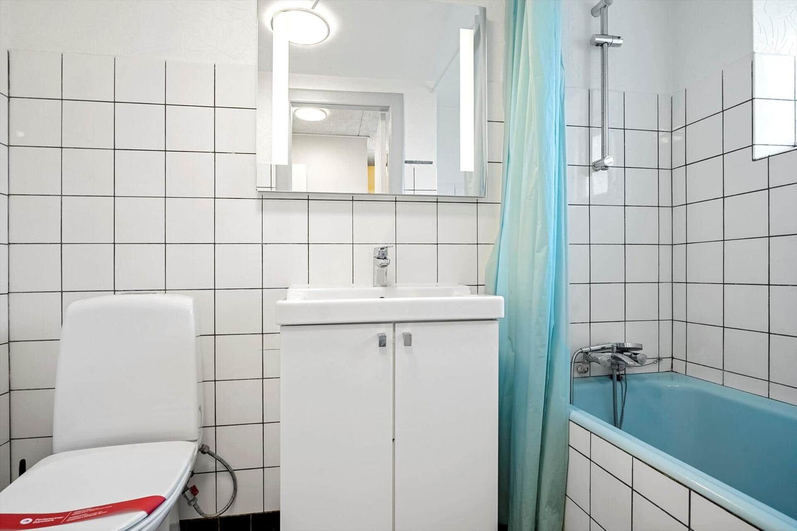 Badezimmer mit Toilette, Waschbecken und Badewanne mit Duschvorhang.