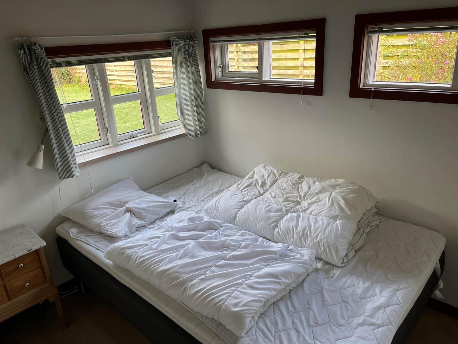Bedroom with bed, windows, and nightstand.