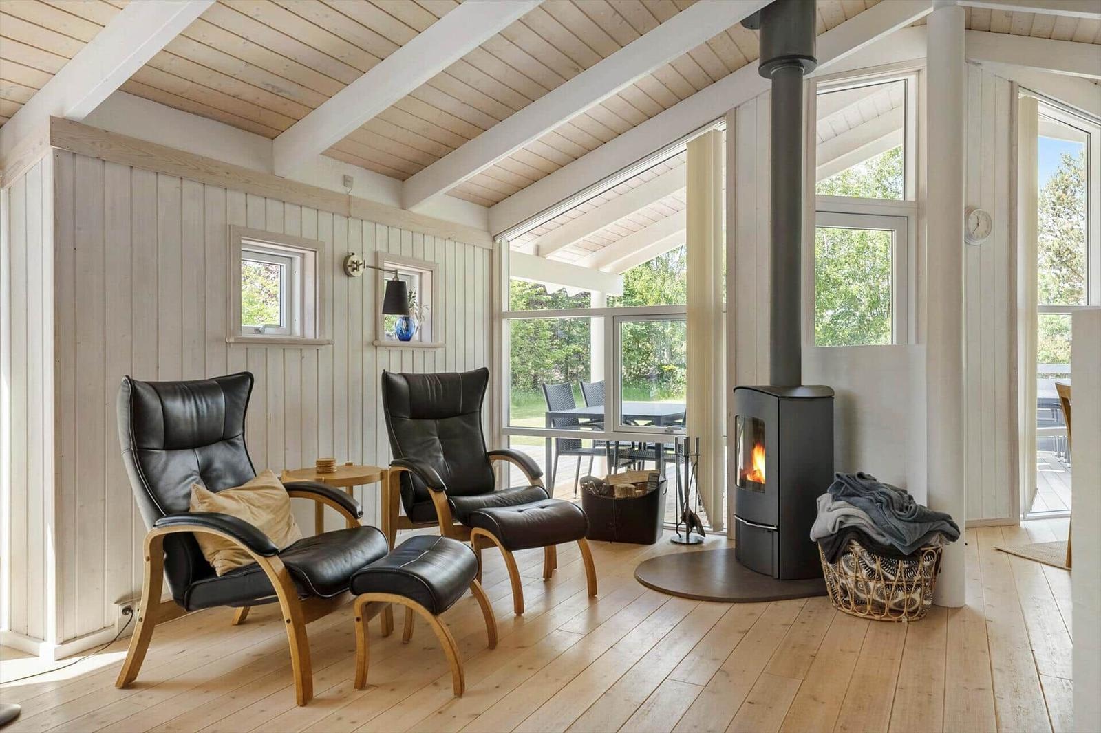 Two black leather armchairs with wooden legs are positioned in front of a wood-burning stove.