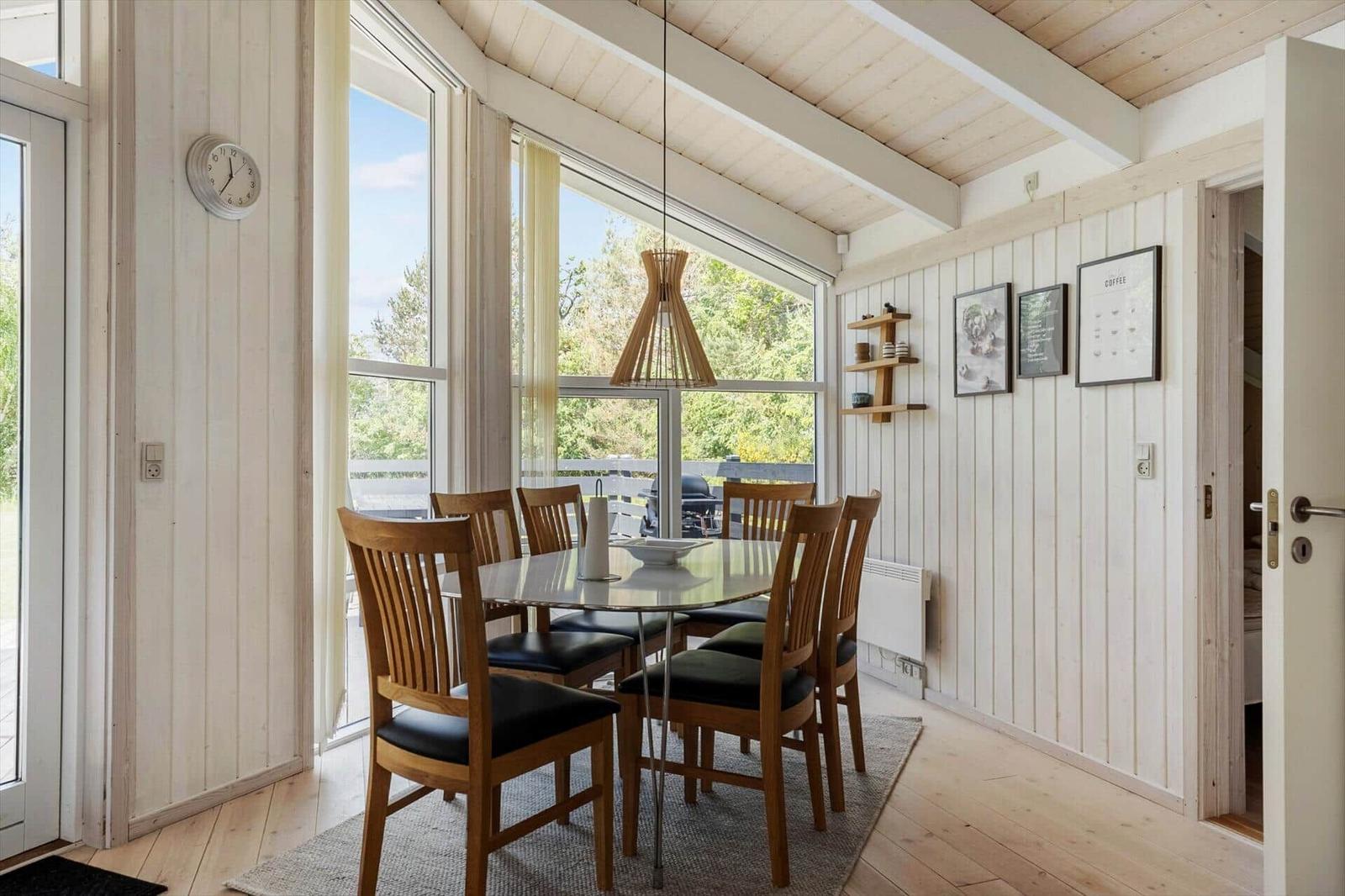 Dining area with wooden chairs, glass top, and large windows to the outside.