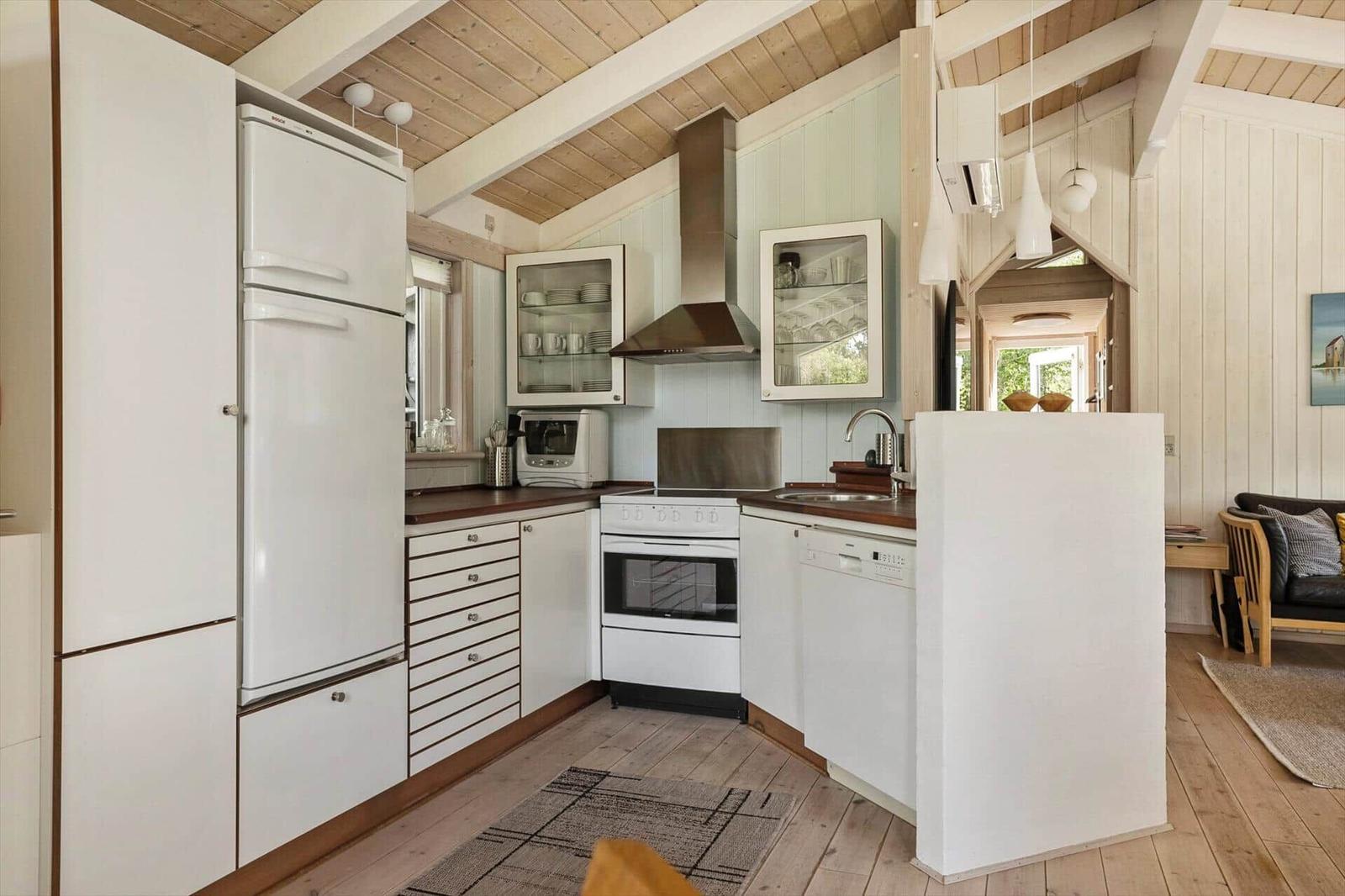 Kitchen with white cabinets, fridge, stove, and sink. Wooden ceiling and floor.