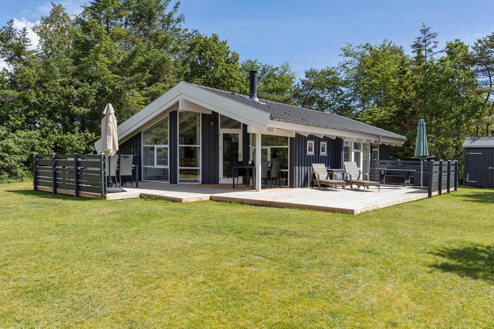 Modern holiday home with terrace, garden, and barbecue area. Surrounded by trees.