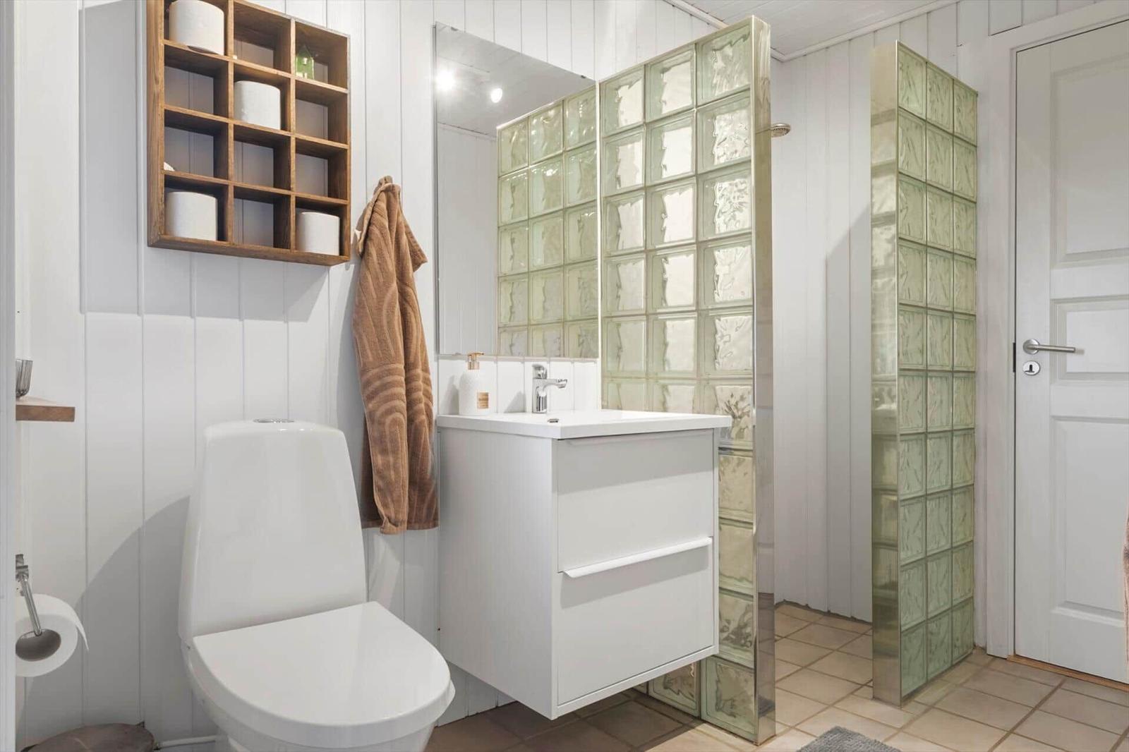 Badezimmer mit Toilette, Waschbecken und Dusche aus Glassteinen.
