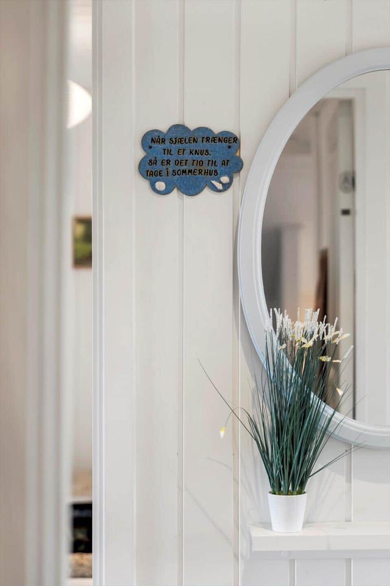 Wand mit runden Spiegel, Pflanze und Schild mit norwegischer Aufschrift.