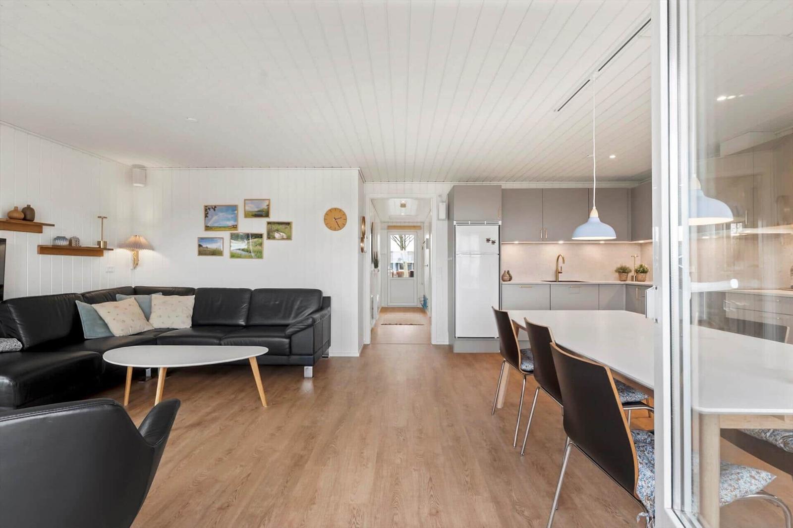 Wohn- und Küchenbereich mit Sofa, Esstisch und Kühlschrank.
