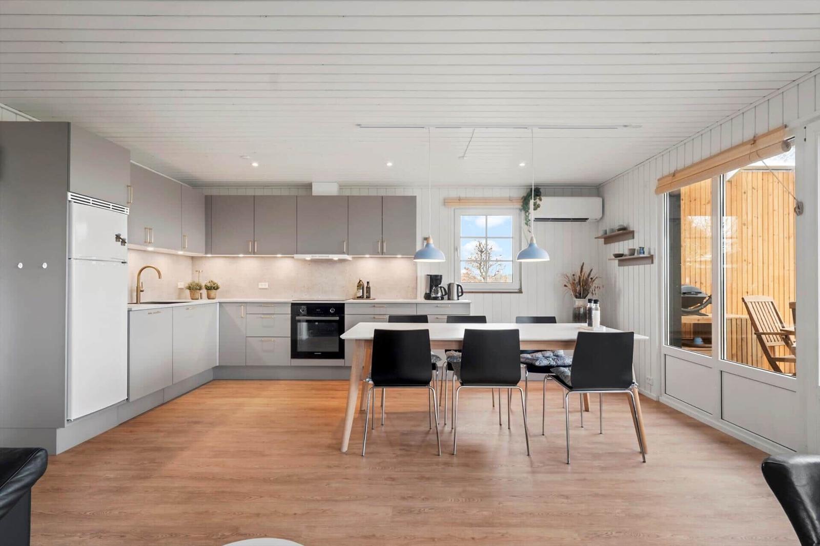 Küche mit Essbereich, Holzboden und Fenster zur Terrasse.