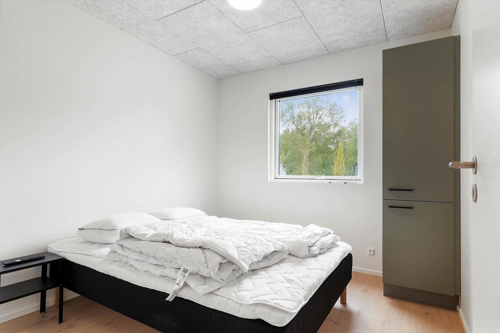 Schlafzimmer mit Bett, Fenster und Kleiderschrank.