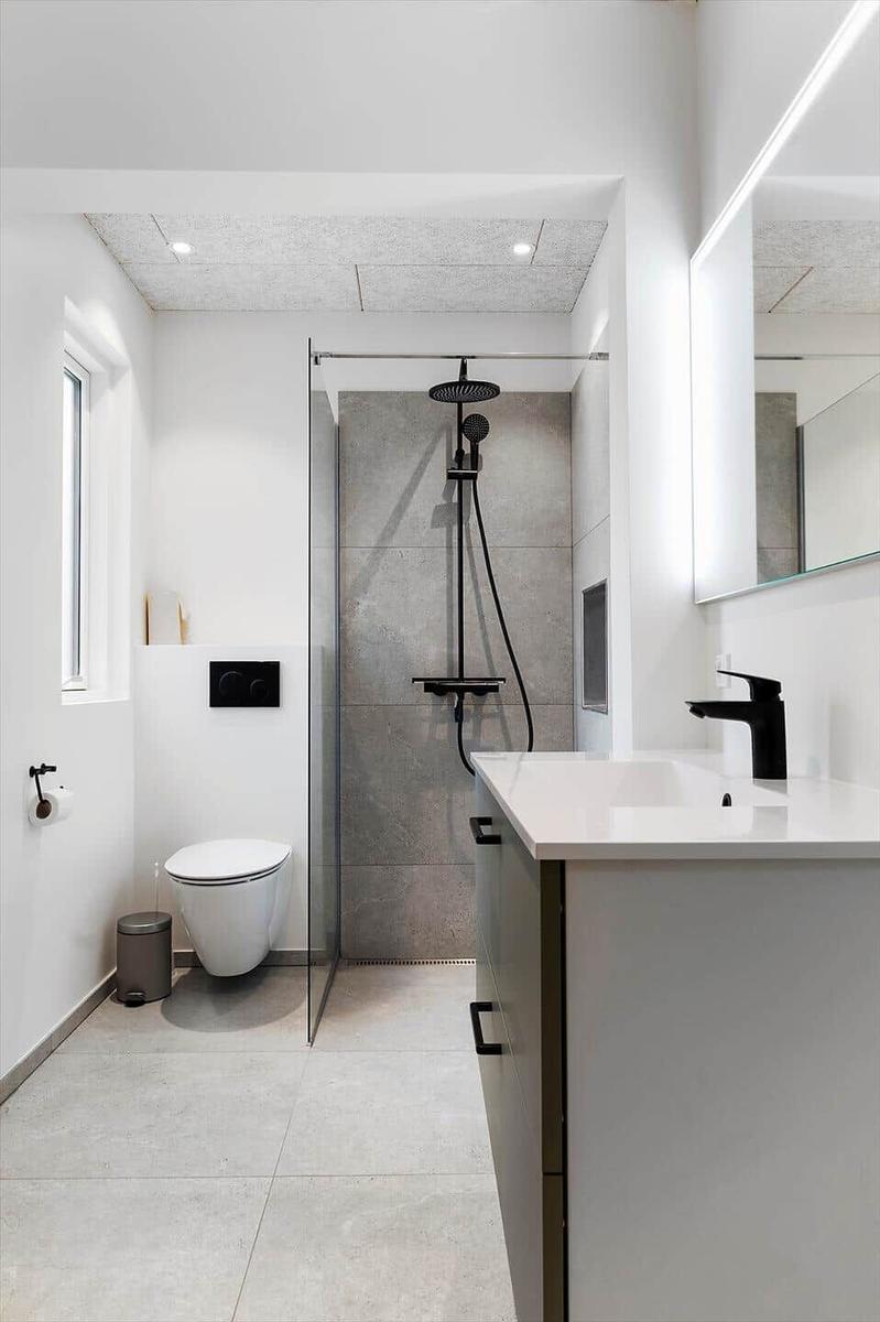 Moderne Dusche mit Glaswand, Waschbecken und Toilette in einem hellen Badezimmer.