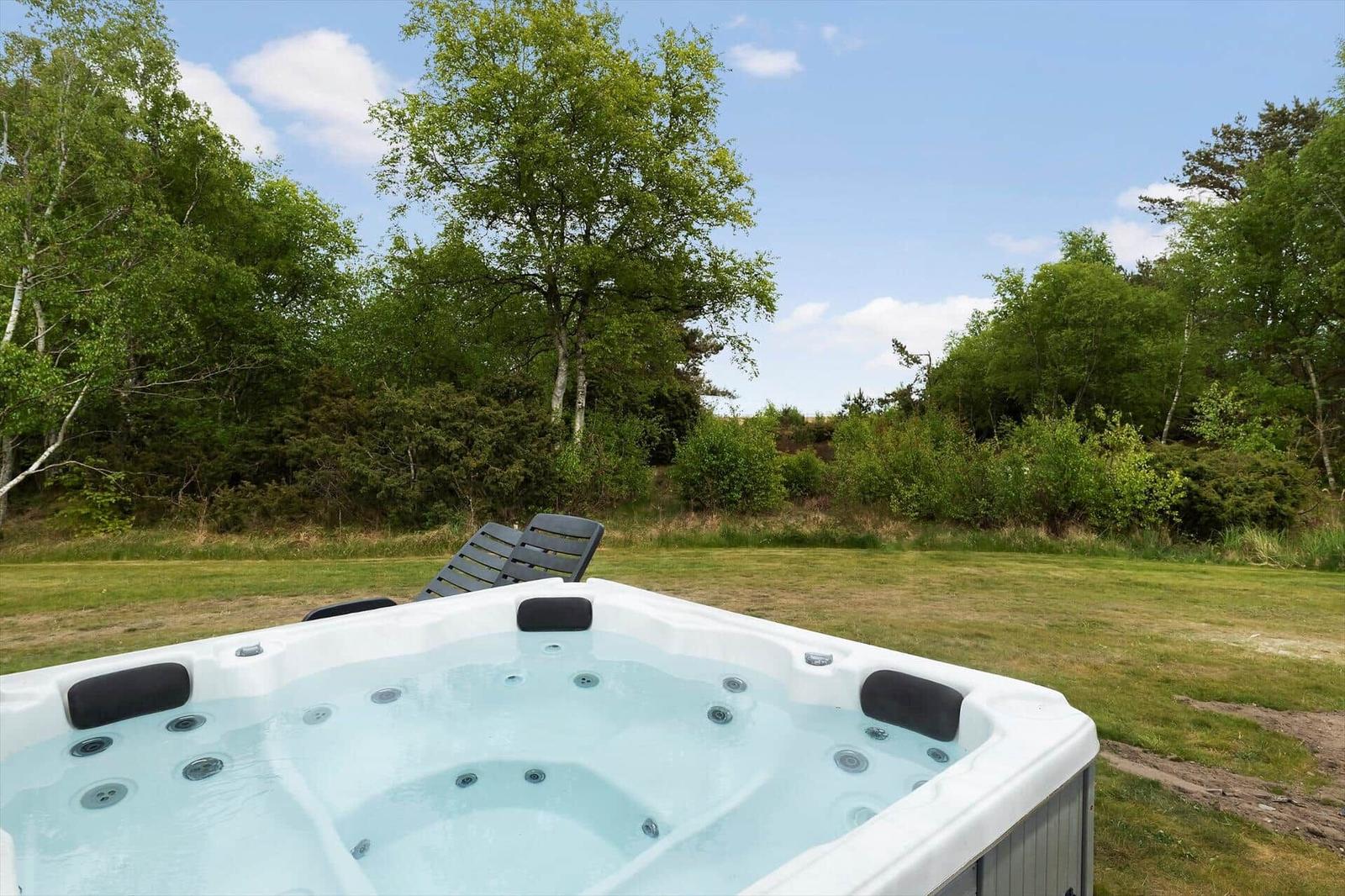 Ein Whirlpool auf einer grünen Wiese mit Bäumen im Hintergrund.