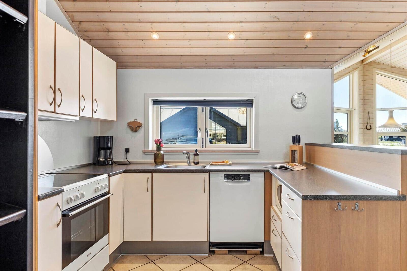 Küche mit Holzdecke, Arbeitsplatten und Fenster zum Blick nach draußen.