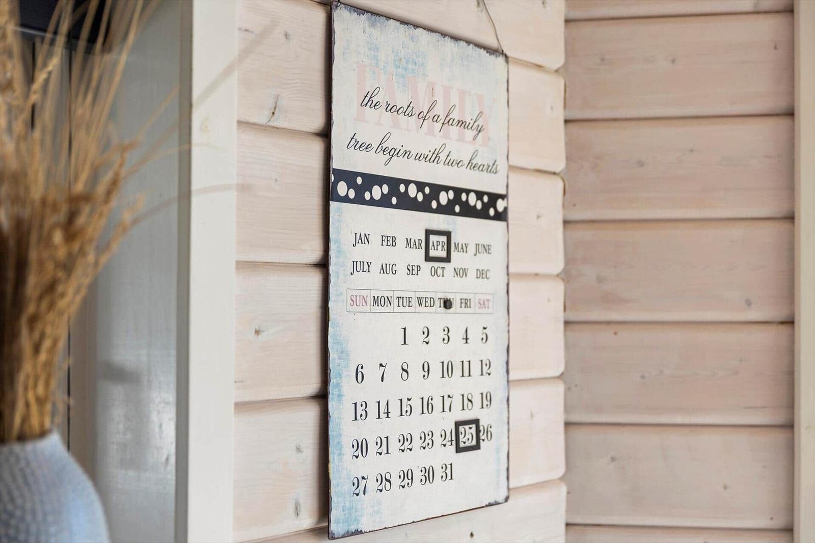 Wandkalender mit Familientext an Holzwand. April und 25. Tag markiert.