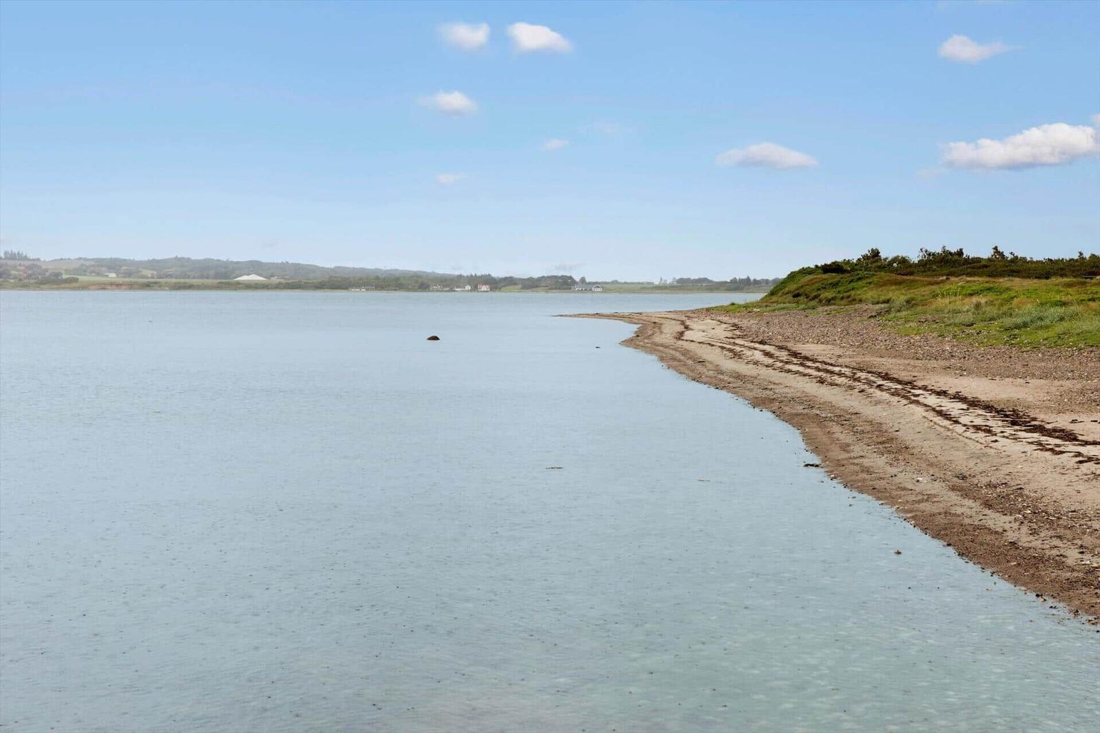 Strandabschnitt mit klarem Wasser und grasbewachsenem Ufer