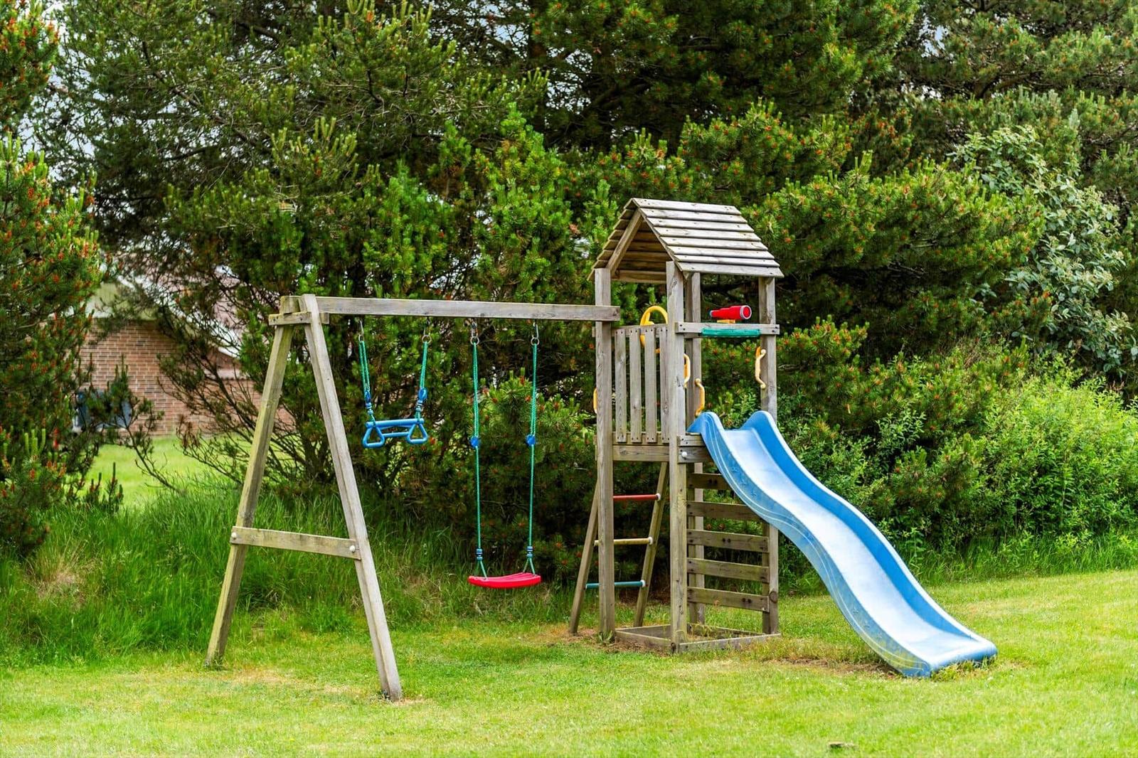 Hinterhof mit Spielplatz, Schaukel und Rutsche auf grünem Rasen.