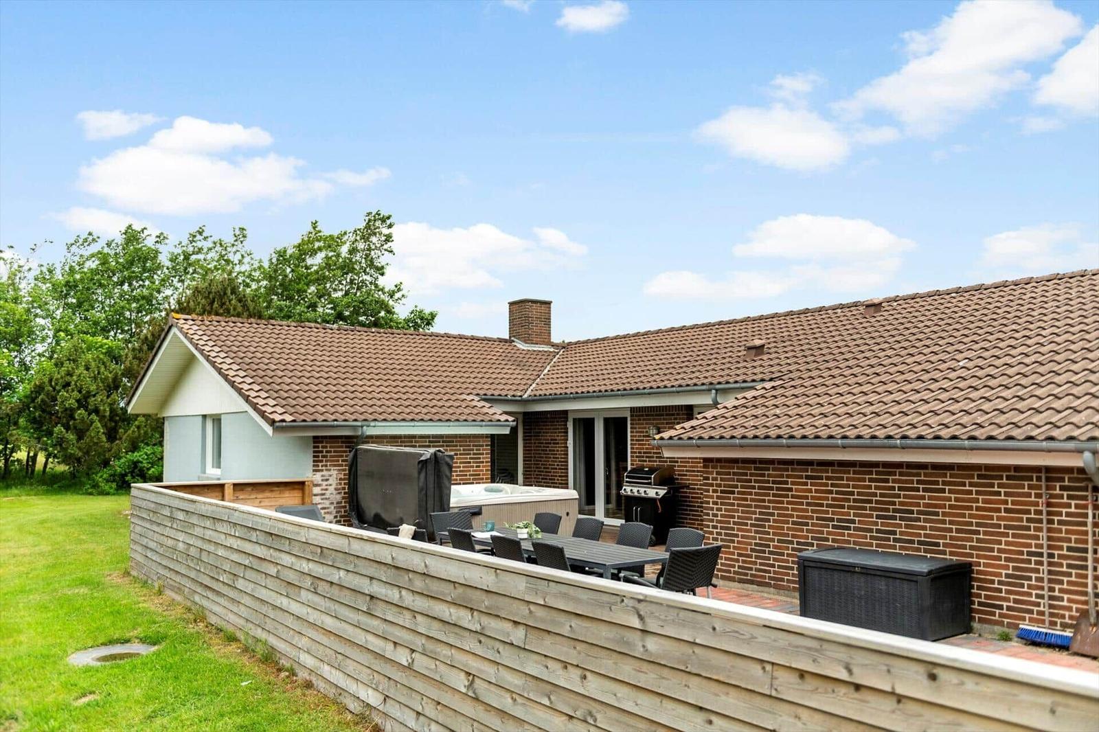 Haus mit Terrasse, Grill und Whirlpool im Garten.