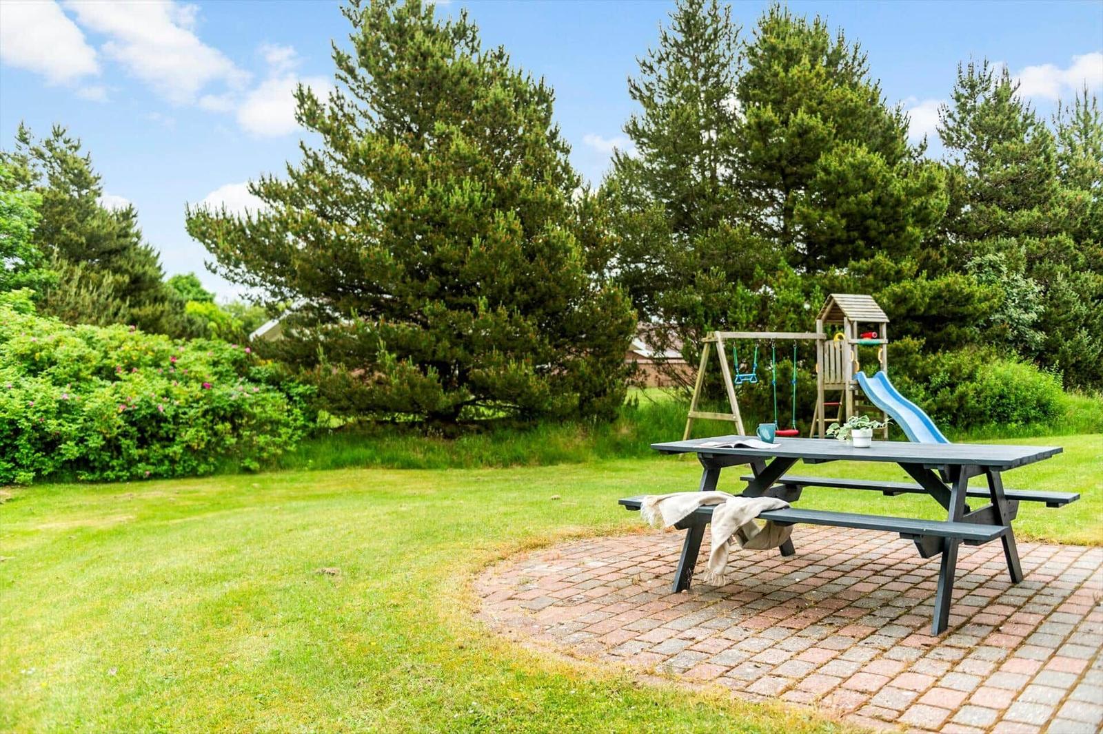 Garten mit Picknicktisch, Spielplatz und Bäumen.