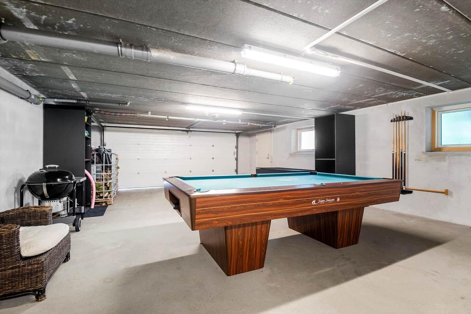 Billiard table with blue felt in a garage with seating and grill.