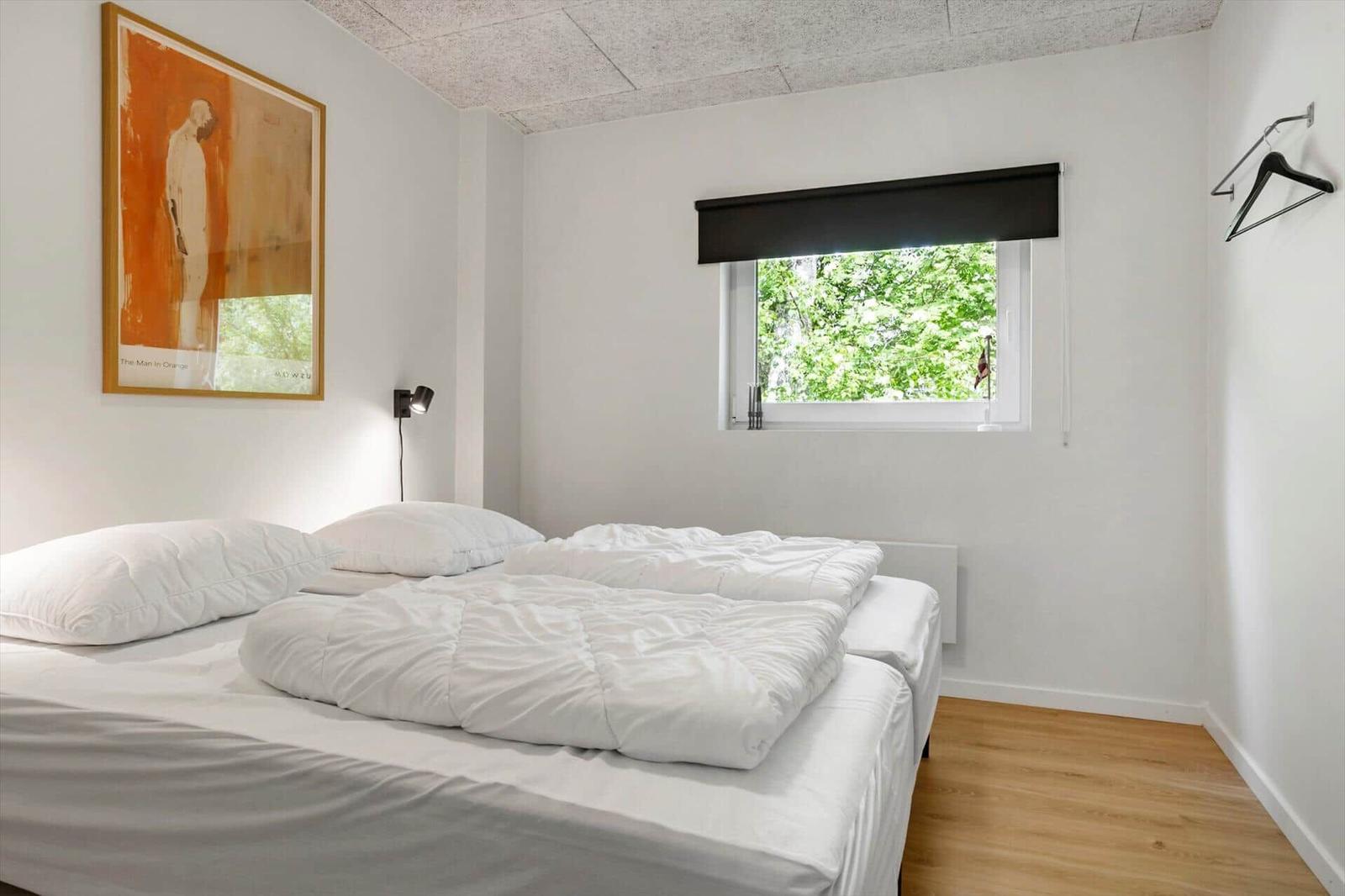 Schlafzimmer mit Bett, Fenster und Wandbild.