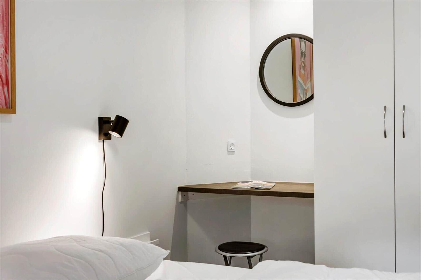 Schlafzimmer mit Bett, Schreibtisch, Spiegel und Kleiderschrank.