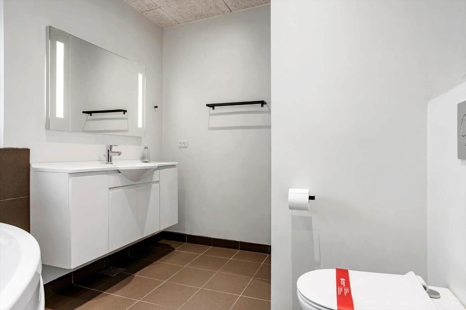 Badezimmer mit Waschbecken, Spiegel und Toilette.