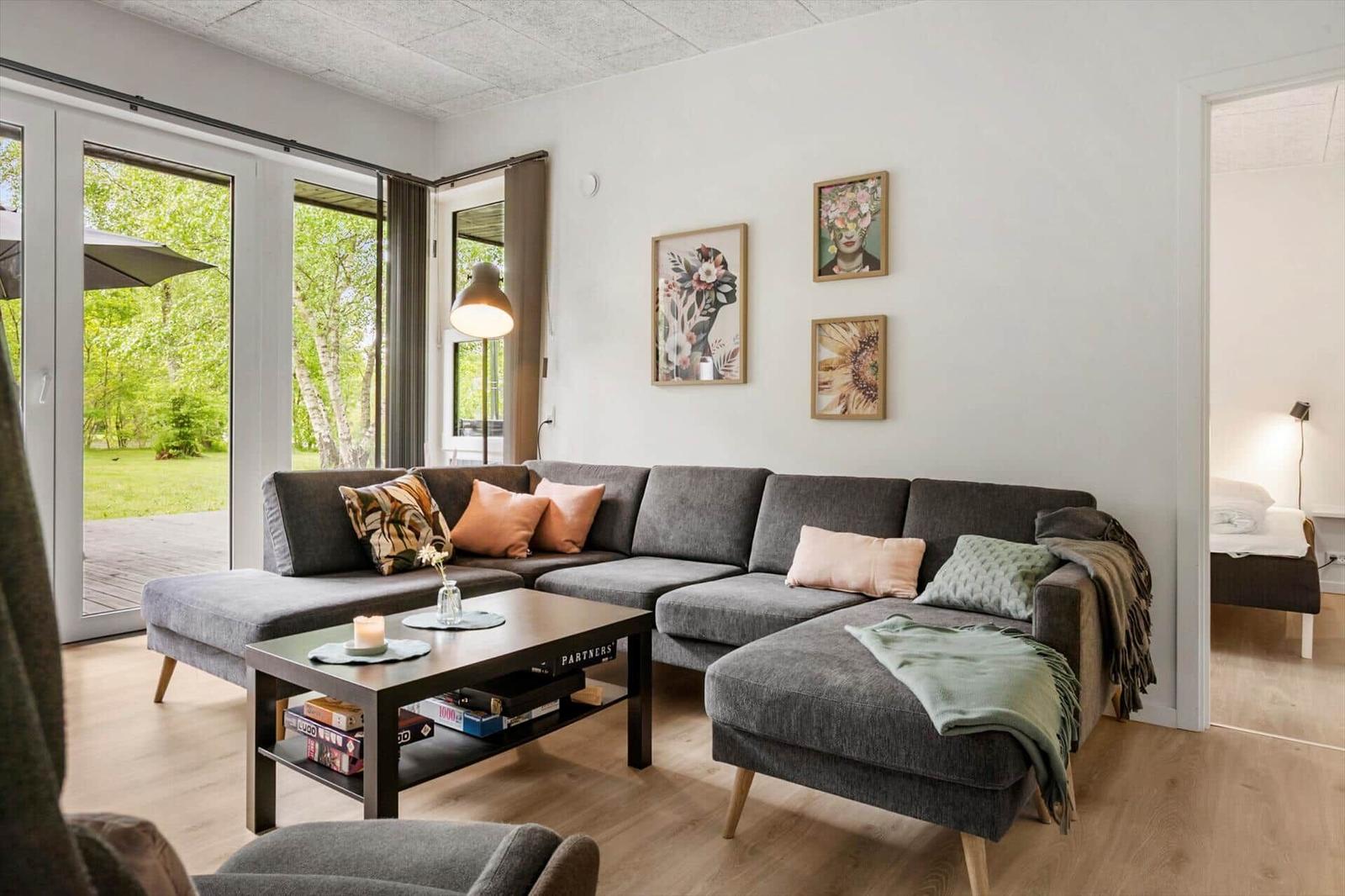 Wohnzimmer mit grauem Sofa, Couchtisch und Blick auf Garten