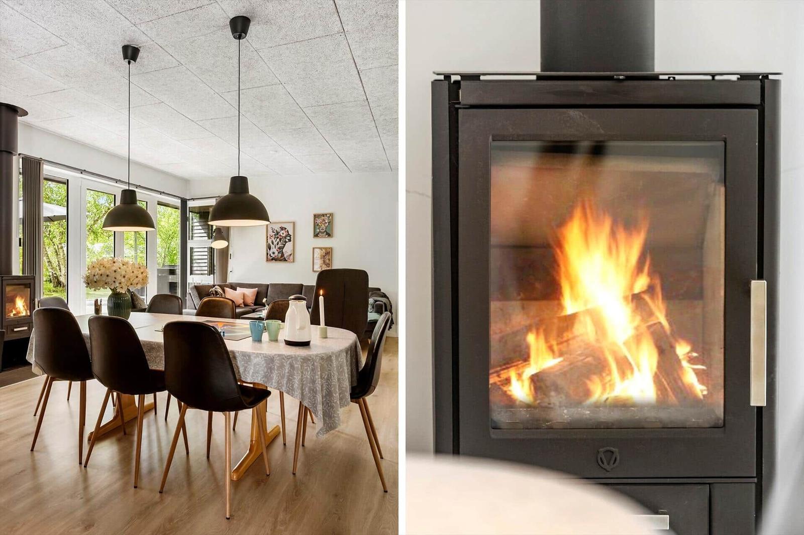 Essbereich mit Tisch, Stühlen und Fenstern. Kamin mit brennendem Holz.